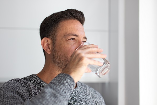 Мъж пие вода. Защо е важно да пием достатъчно течности през зимата?